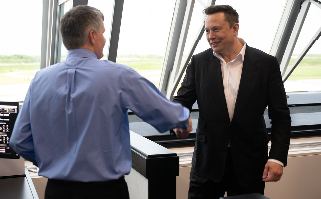Elon Musk shaking hands with a man
